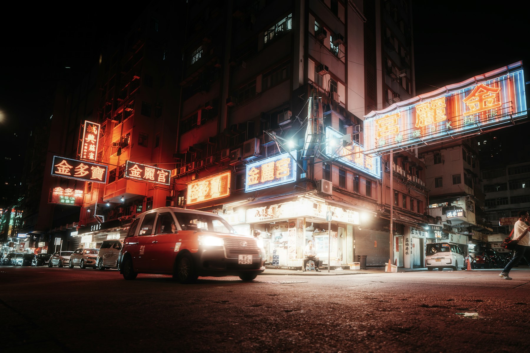 Red neon lights glow along a city street at night