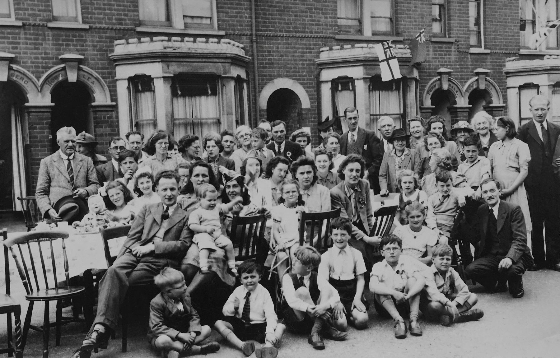 A historic black and white photograph of a British street gathering